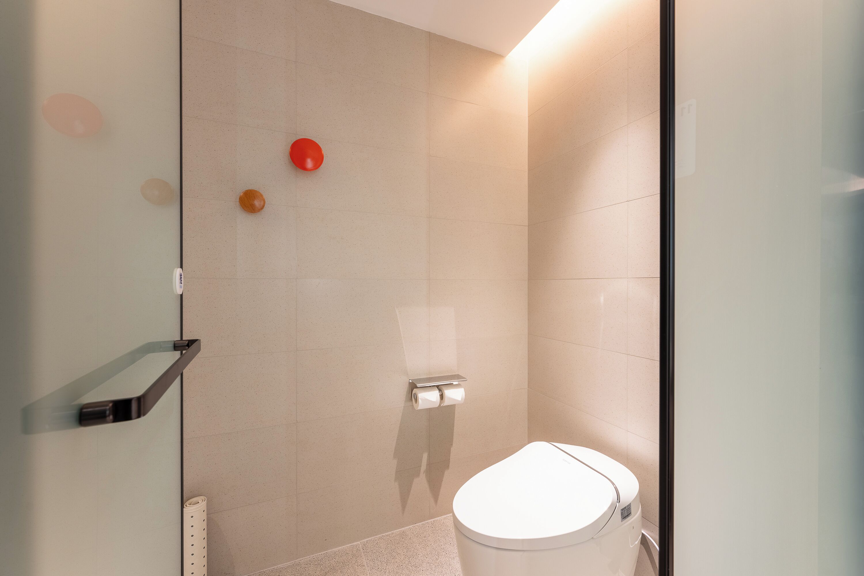 A modern bathroom with a glass shower enclosure, a toilet, and a towel rack.