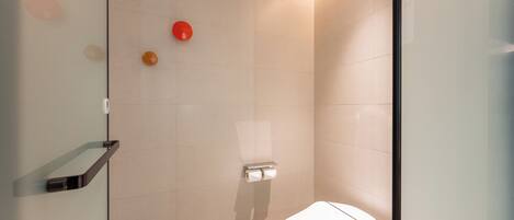 A modern bathroom with a glass shower enclosure, a toilet, and a towel rack.