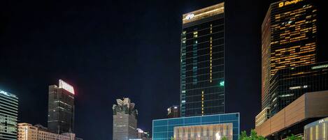 A nighttime cityscape with modern high-rise buildings, including a prominent building with a sign that reads "Shangri-La."