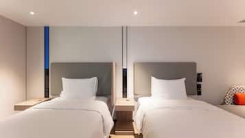 A modern hotel room with two beds, a small table, and a wall-mounted phone.
