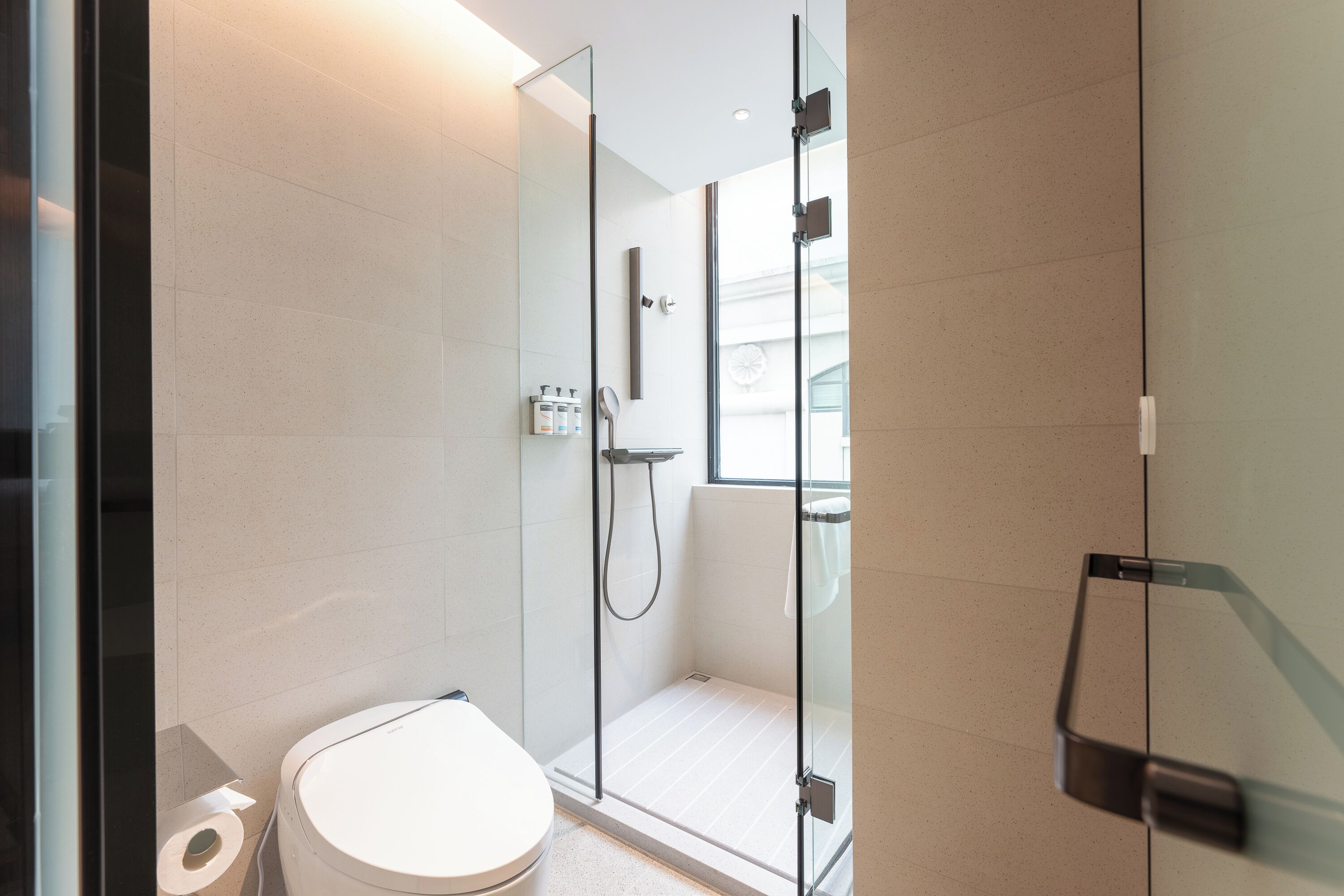 Un baño moderno con ducha acristalada, inodoro y lavamanos.