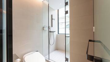 Un baño moderno con ducha acristalada, inodoro y lavamanos.