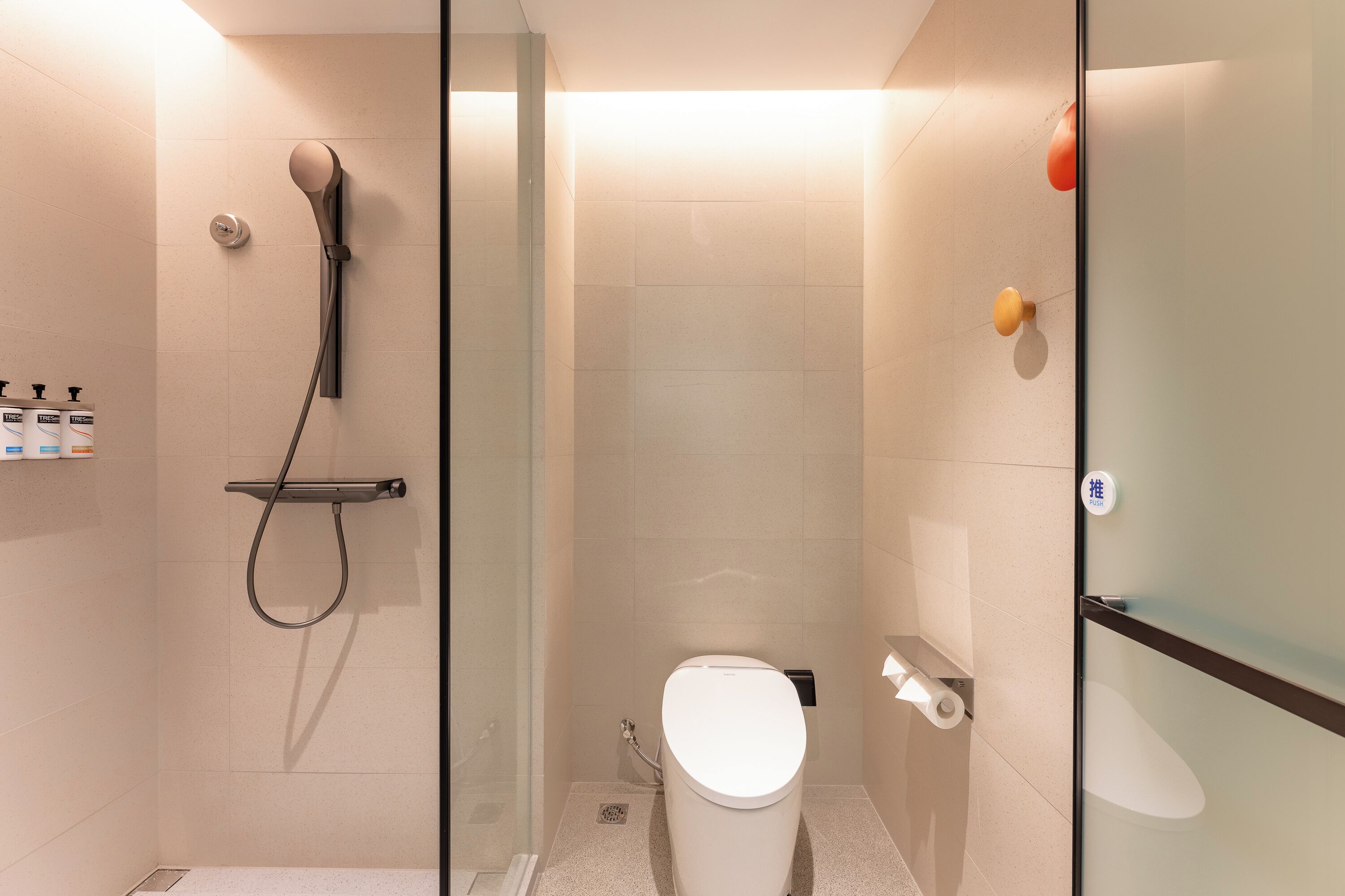 A modern bathroom with a glass shower enclosure, a toilet, and a glass partition.