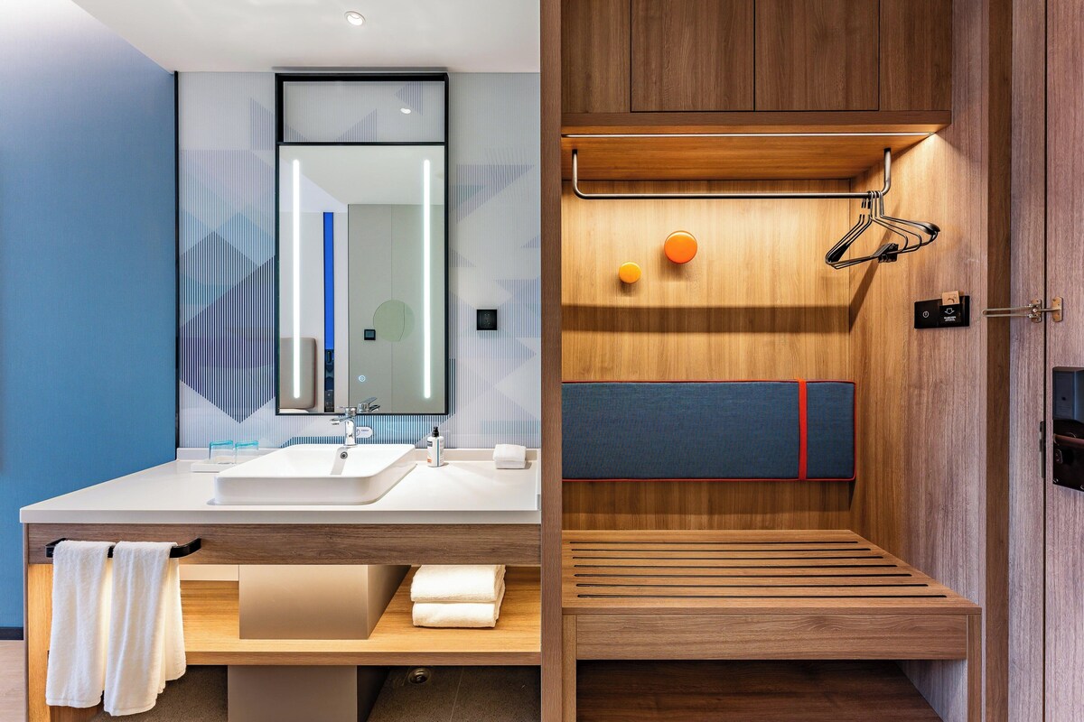 Un baño moderno con lavamanos dobles, un espejo grande y un mueble de tocador de madera.