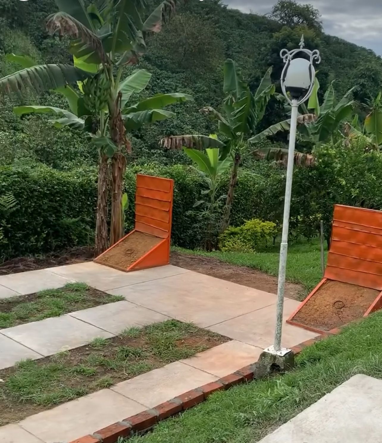 A garden area with a paved walkway, a wooden bench, and a street lamp.