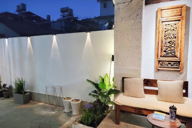A patio area with a cushioned seating arrangement, a small table, and a decorative wall piece.