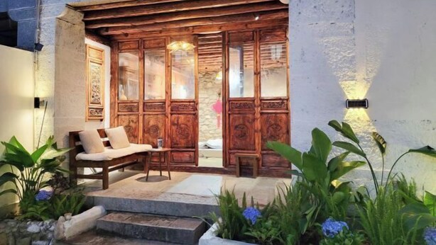 A wooden entrance with a bench and steps leading to a covered area. - Zuji Youth Hostel (Dali City)