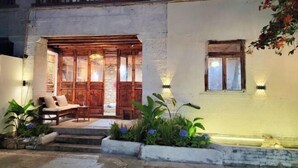 A traditional building with a wooden entrance, steps leading to a seating area, and a small garden with plants. - Zuji Youth Hostel (Dali City)
