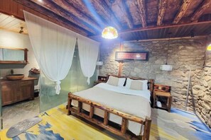 A rustic bedroom with a wooden bed, stone walls, a stone fireplace, and a canopy bed. - Zuji Youth Hostel (Dali City)