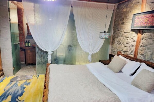 A bed with white linens, a stone wall, and a hanging light fixture. - Zuji Youth Hostel (Dali City)