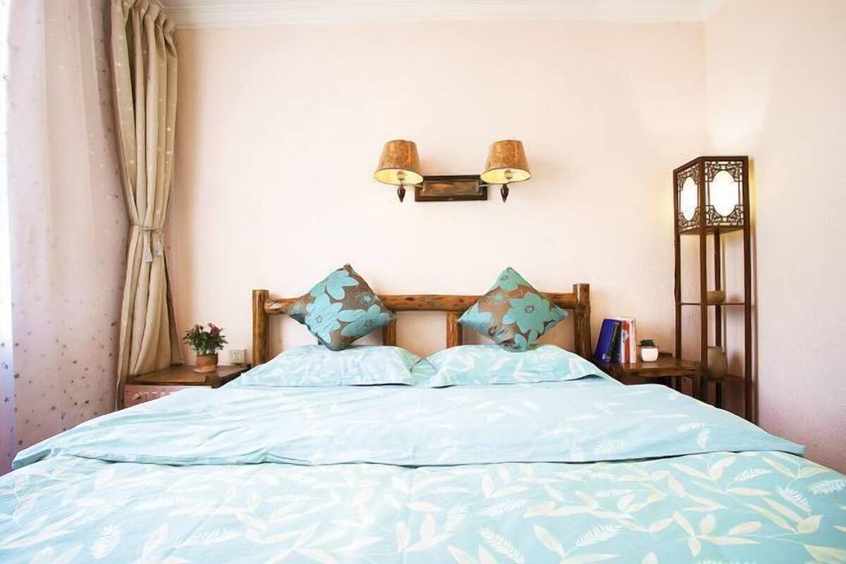 Une chambre à coucher comprenant un lit, deux lampes fixées au mur, une table de chevet avec une plante et une commode de style traditionnel.