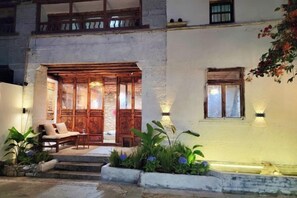 A building with a wooden entrance, steps leading to a porch, and outdoor seating. - Zuji Youth Hostel (Dali City)