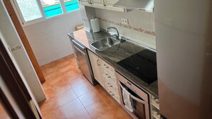 A compact kitchen with a sink, stove, and dishwasher. - Charming 2-bedroom apartment with AC, WiFi in lovely Granada (Granada)
