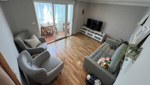 A modern living room with a grey sofa, a grey armchair, and a TV on a white entertainment unit. - Charming 2-bedroom apartment with AC, WiFi in lovely Granada (Granada)