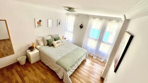 A bedroom with a bed, bedside tables, a mirror, and a window with curtains. - Charming 2-bedroom apartment with AC, WiFi in lovely Granada (Granada)
