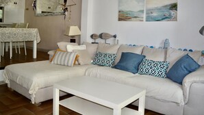 Een woonkamer met een bank, een salontafel, een eettafel met stoelen en wanddecoratie.