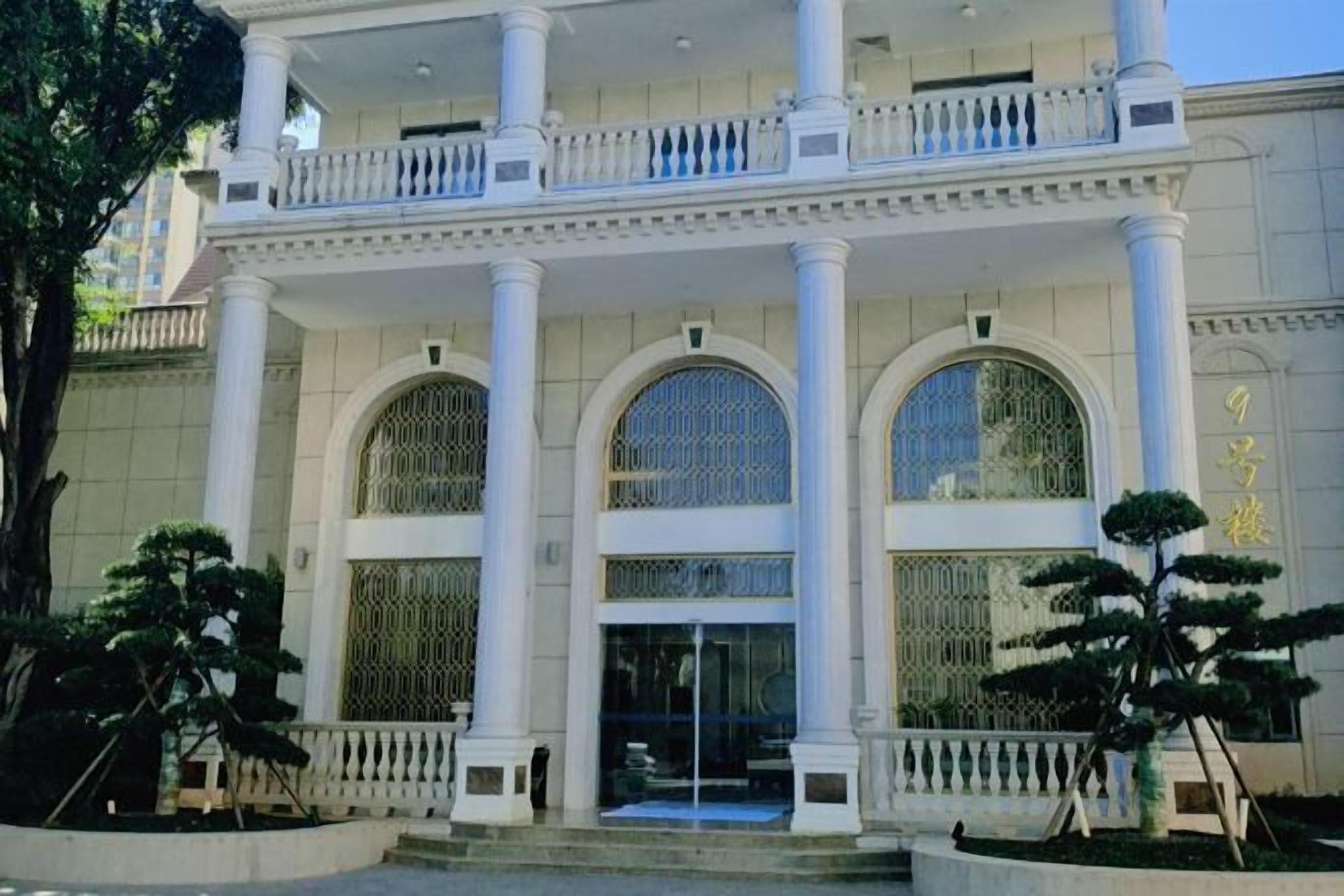 Ein Gebäude mit einem prachtvollen Eingang, großen Bogenfenstern und einer symmetrischen Fassade mit Säulen.