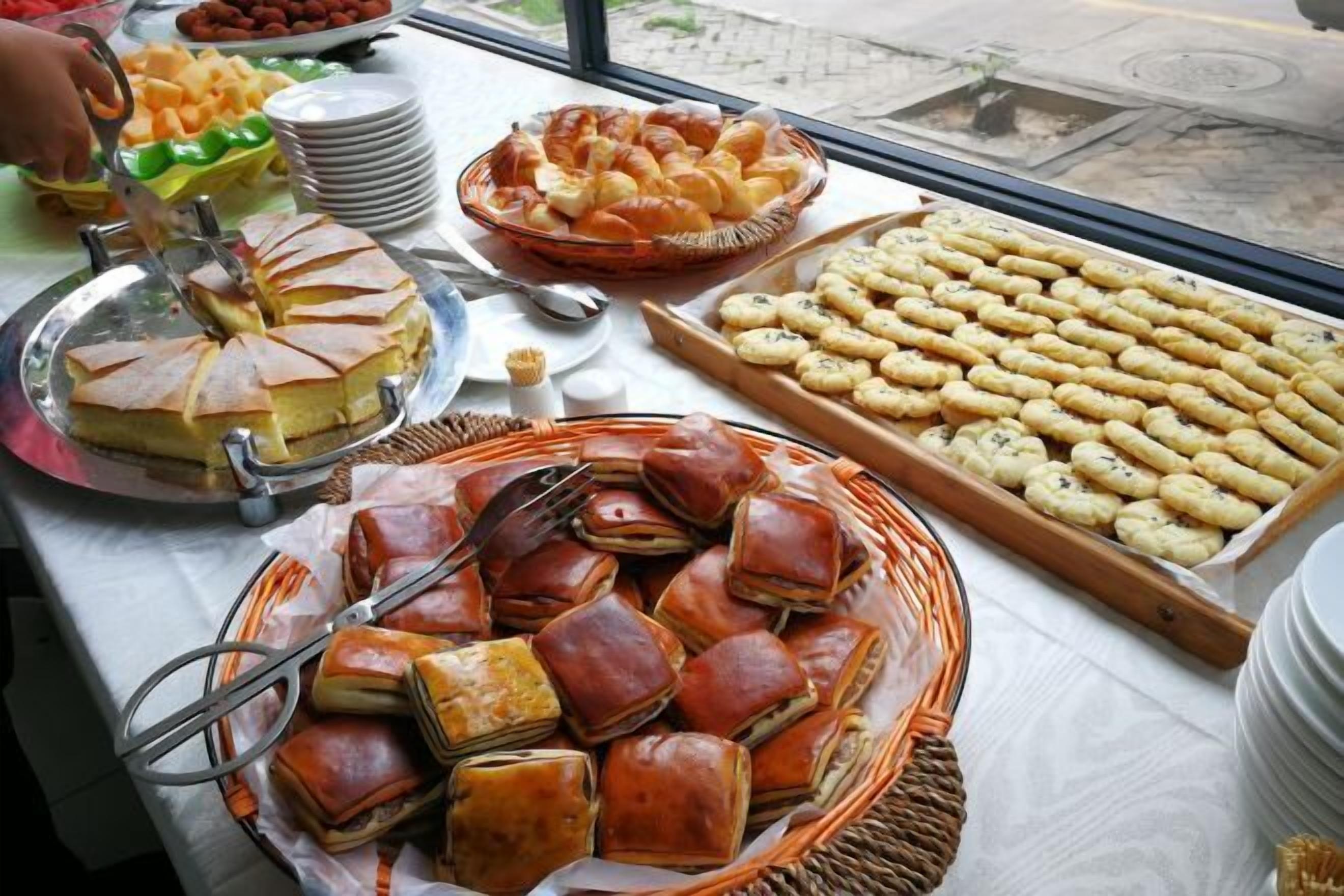 Una mesa de bufé con diferentes alimentos, como pasteles, sándwiches y un pastel.