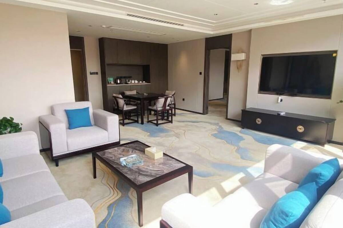 A modern living room with a sofa set, a coffee table, a dining area, and a TV.