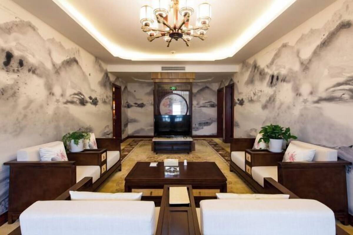 A hotel lobby with a central seating area, a chandelier, and a television screen.