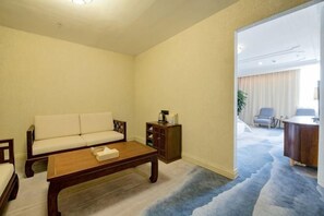 A living room with a sofa, coffee table, and a cabinet. There is a door leading to another room. - Xinda Hotel (Dali High-Speed Railway Station & Erhai Lake Park) (Dali)