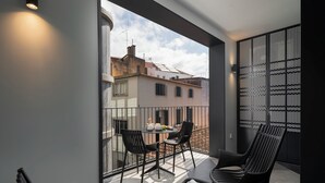 Un balcon avec une table et des chaises, un magazine et une vue sur les immeubles.