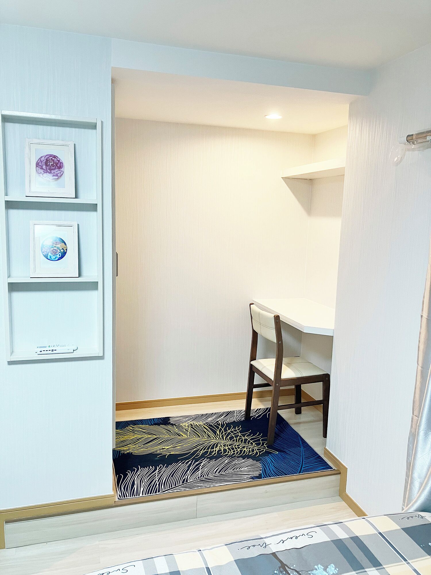 A room with a desk, chair, and a patterned rug. There are three framed pictures on the wall.
