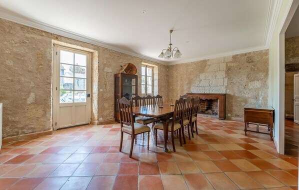 Une salle à manger avec une grande table et des chaises en bois, une cheminée et une vue par la fenêtre.