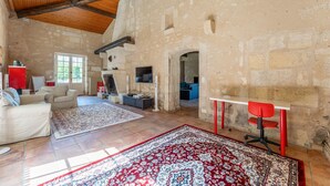 Amplia sala de estar con techo alto, chimenea, televisor y una butaca roja.