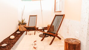 A patio area with two wooden chairs, a large umbrella, and a potted plant. - Kalathos House 2 (Lisbon)