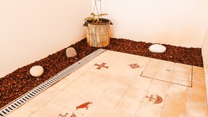 A tiled floor with various symbols, a small plant in a bamboo pot, and a stone on the ground. - Kalathos House 2 (Lisbon)
