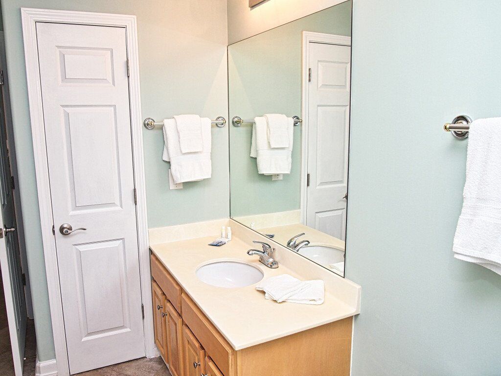 Un baño con lavamanos doble, un espejo grande y dos toallas colgadas en barras para toallas.