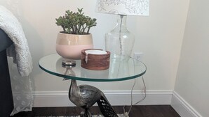 A glass table with a potted plant, a lamp, and a decorative bird sculpture.