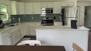 A modern kitchen with white cabinets, stainless steel appliances, and a central island.