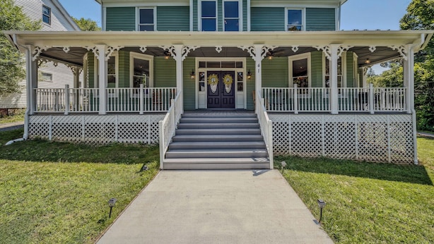A two-story house with a front porch, a central staircase, and a small tower-like structure on the roof. - Appalachian Suite In Town!- The Grand Castalian Inn B&B (Berkeley Springs)