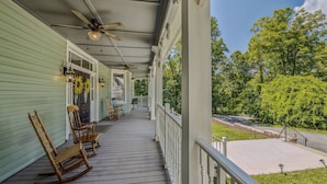 A covered porch with rocking chairs, a ceiling fan, and a view of a green landscape. - Appalachian Suite In Town!- The Grand Castalian Inn B&B (Berkeley Springs)