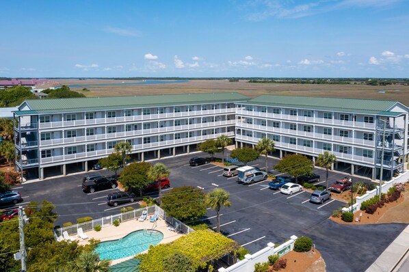 A multi-story hotel with a pool and parking lot.