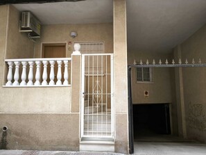 L'ingresso di un edificio con una porta chiusa da cancello, una piccola finestra e un condizionatore d'aria a parete.