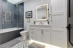 A modern bathroom with a bathtub, toilet, and vanity. - Luxury Clarendon 4-BR Homestay - McVeigh (Arlington)
