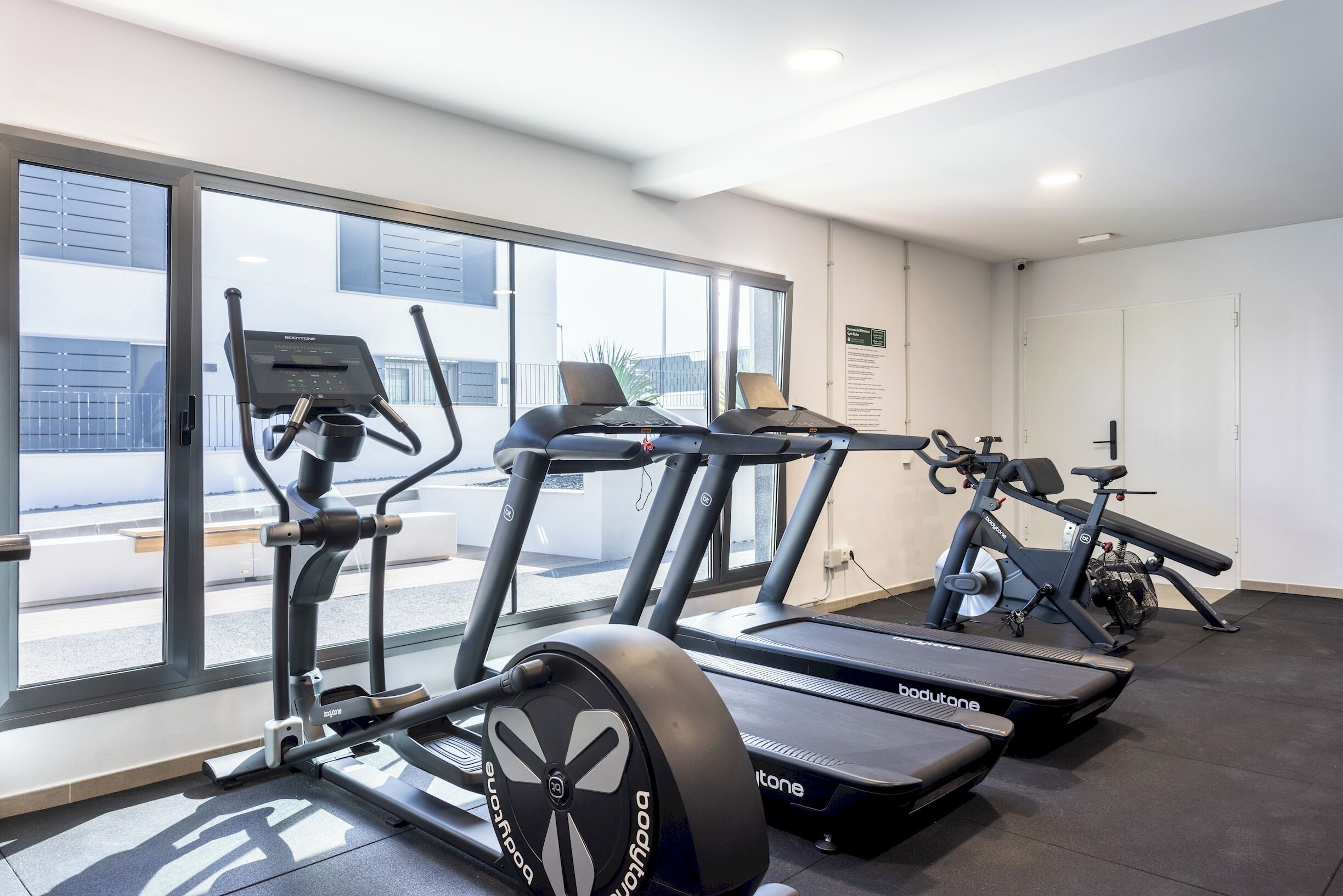 Et fitnesscenter med løbebånd, crosstrainere og en motionscykel.