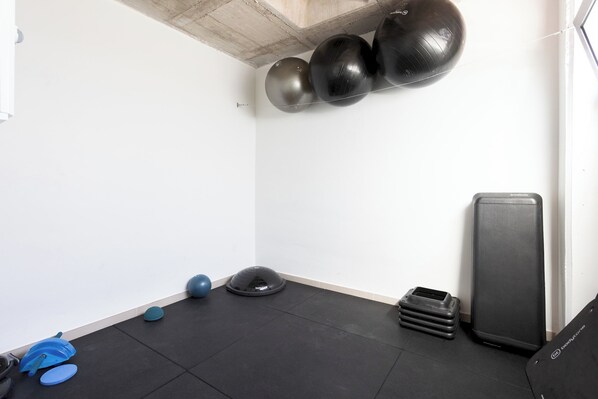 Une salle de sport équipée de matériel d’exercice, notamment un grand ballon d’exercice noir, un ballon d’exercice bleu et un tapis bleu.
