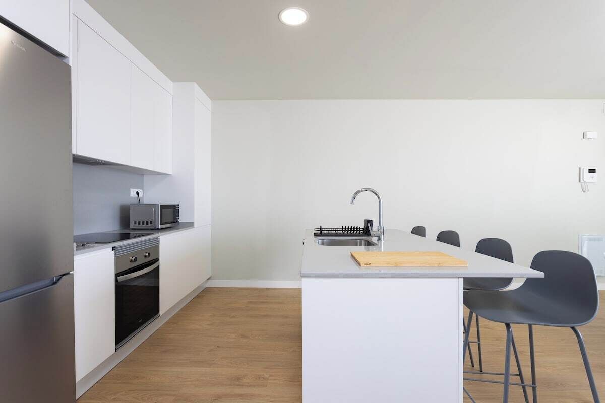 A modern kitchen with white cabinetry, a built-in oven, a microwave, and a sink.