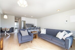 Ein modernes Wohnzimmer mit einem grauen Sofa, einem kleinen Couchtisch und einem Essbereich mit Stühlen und einem Tisch.