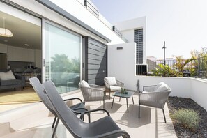 A modern outdoor patio with seating and a glass door leading to a living area. - Home2Book Nordés Apartment Pool & Terrace, Abades (Abades)