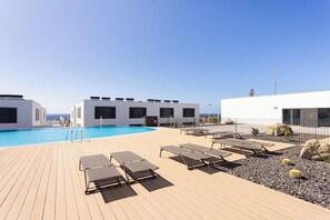A rooftop pool area with lounge chairs, a pool, and a building with a white facade. - Home2Book Nordés Apartment Pool & Terrace, Abades (Abades)