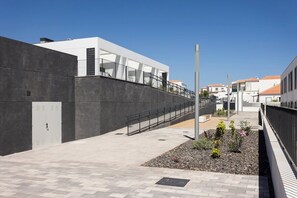 Ein modernes Gebäude mit Betonfassade, einer Metalltreppe und einem gepflasterten Weg.