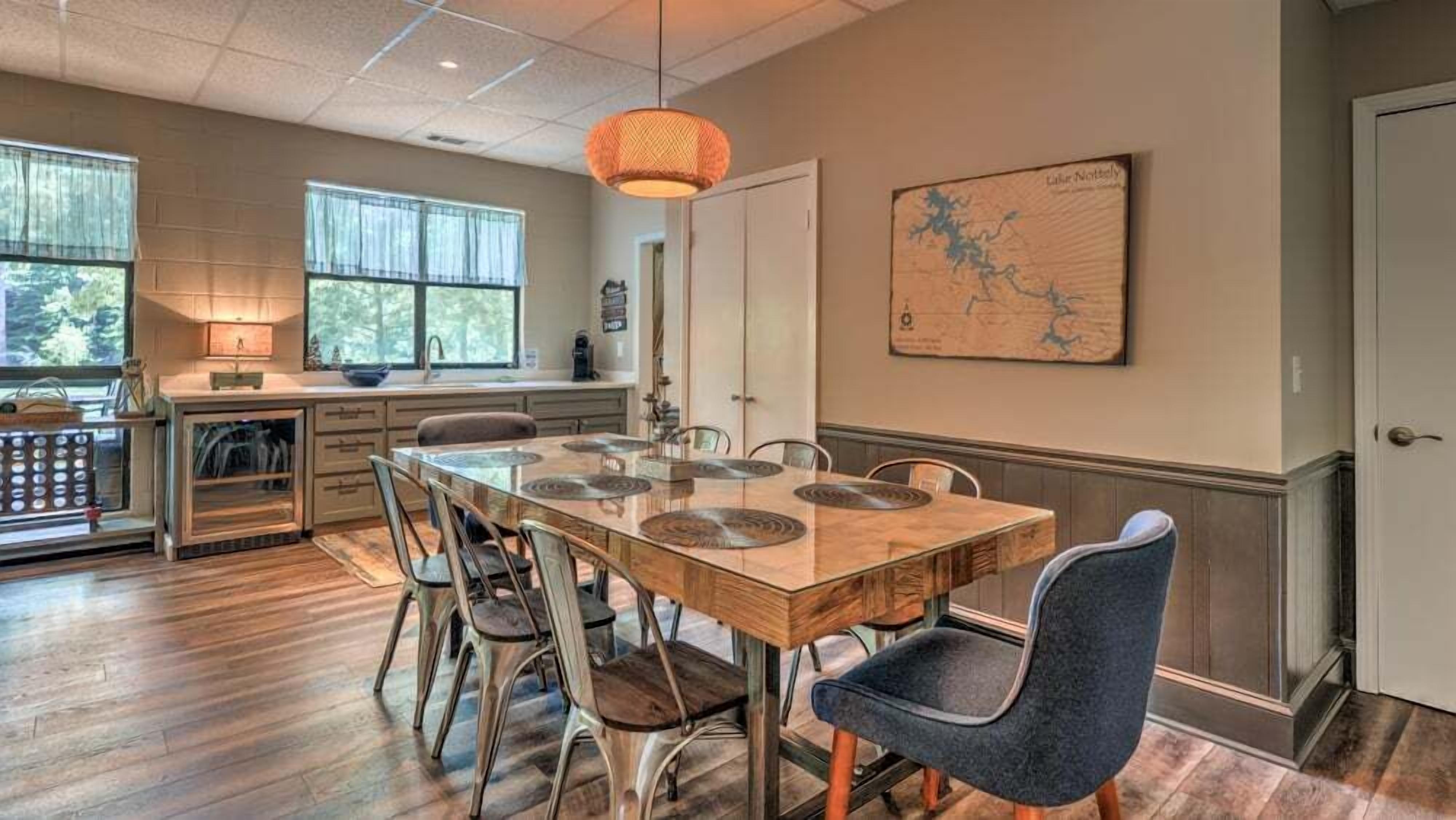 A dining area with a wooden table and chairs, a map on the wall, and a window with curtains.