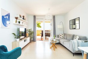 Un salon moderne avec un canapé, un téléviseur et des plantes.