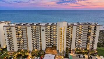 A multi-story hotel with a pool area and a view of the ocean.