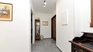 A hallway with a piano, a door, and a cabinet with decorative items. - MaryGiò - Blue Room (Salerno)